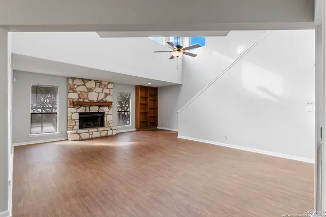 an empty room with wooden floor cabinet and windows