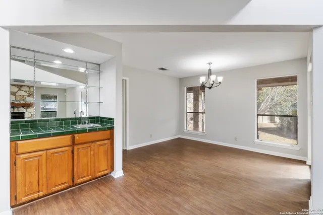 a view of a room with wooden floor chandelier and windows