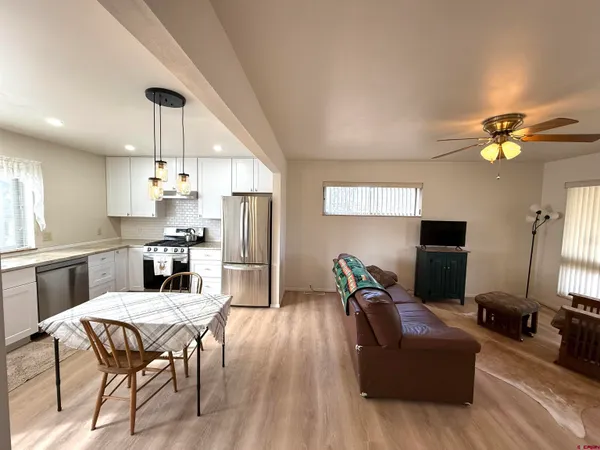 a living room with stainless steel appliances kitchen island granite countertop furniture and a chandelier