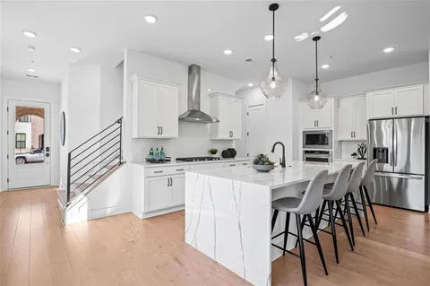 a kitchen with stainless steel appliances kitchen island granite countertop a stove a sink a refrigerator and a dining table with wooden floor