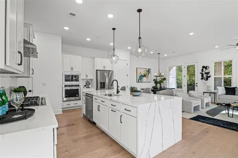 a large white kitchen with lots of counter space wooden floor and appliances