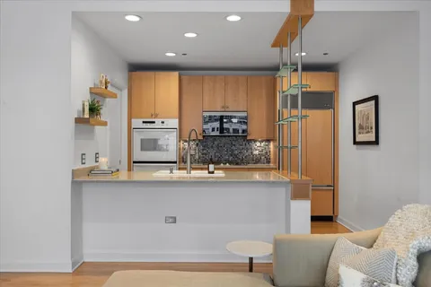 a kitchen with stainless steel appliances a sink a refrigerator a center island and wooden floor