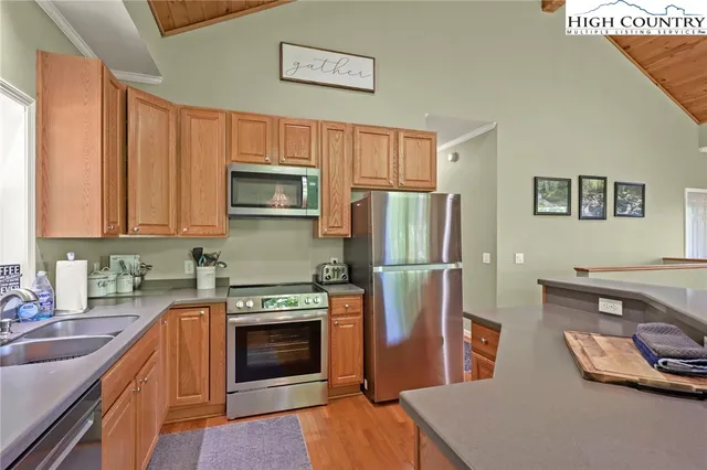 a kitchen with stainless steel appliances a stove a refrigerator a sink a stove with wooden cabinets