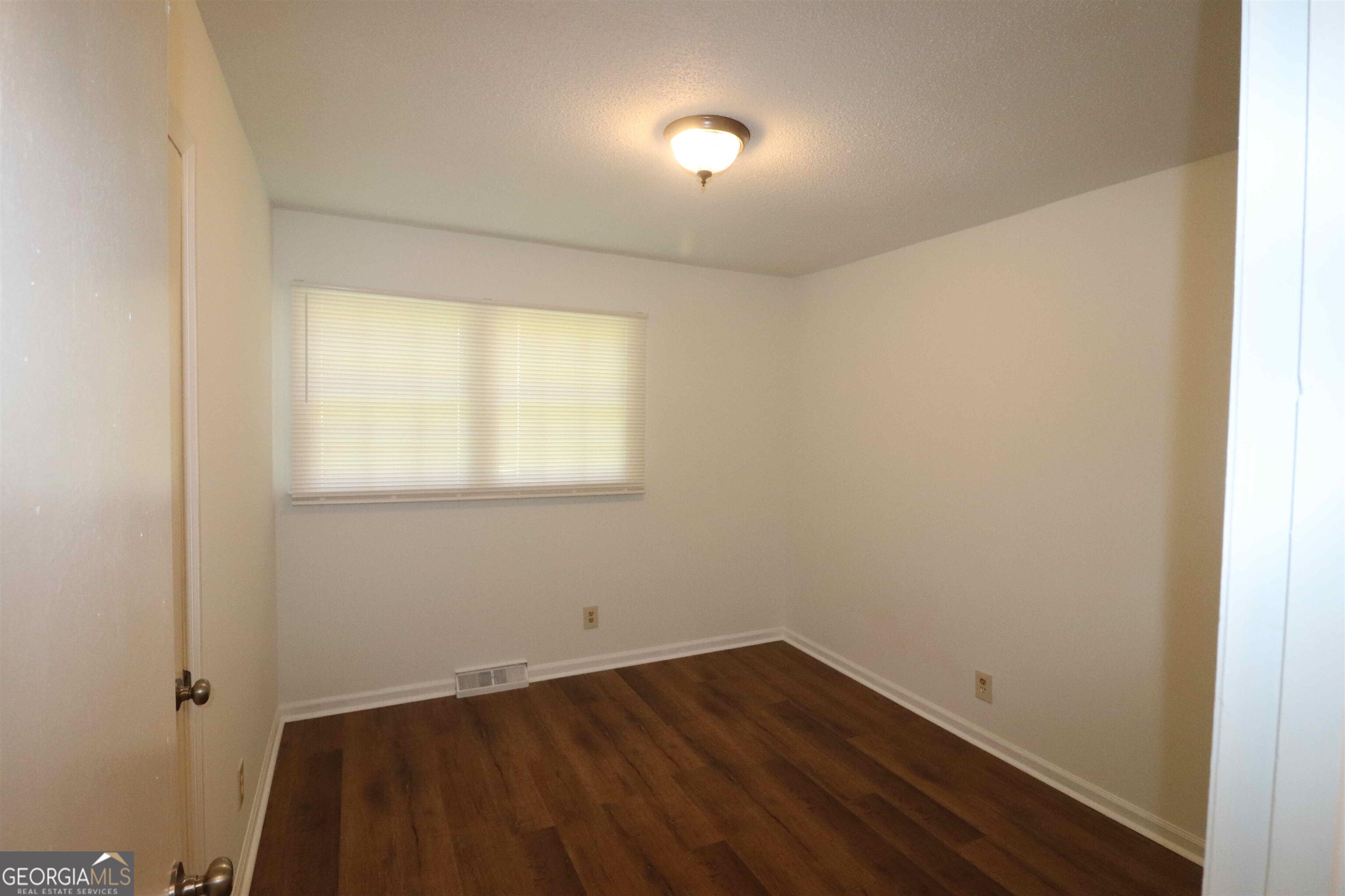 156 Deacon J Simmons Road Southwest Milledgeville, GA 31061 - Photo 12 of 22 an empty room with wooden floor and windows