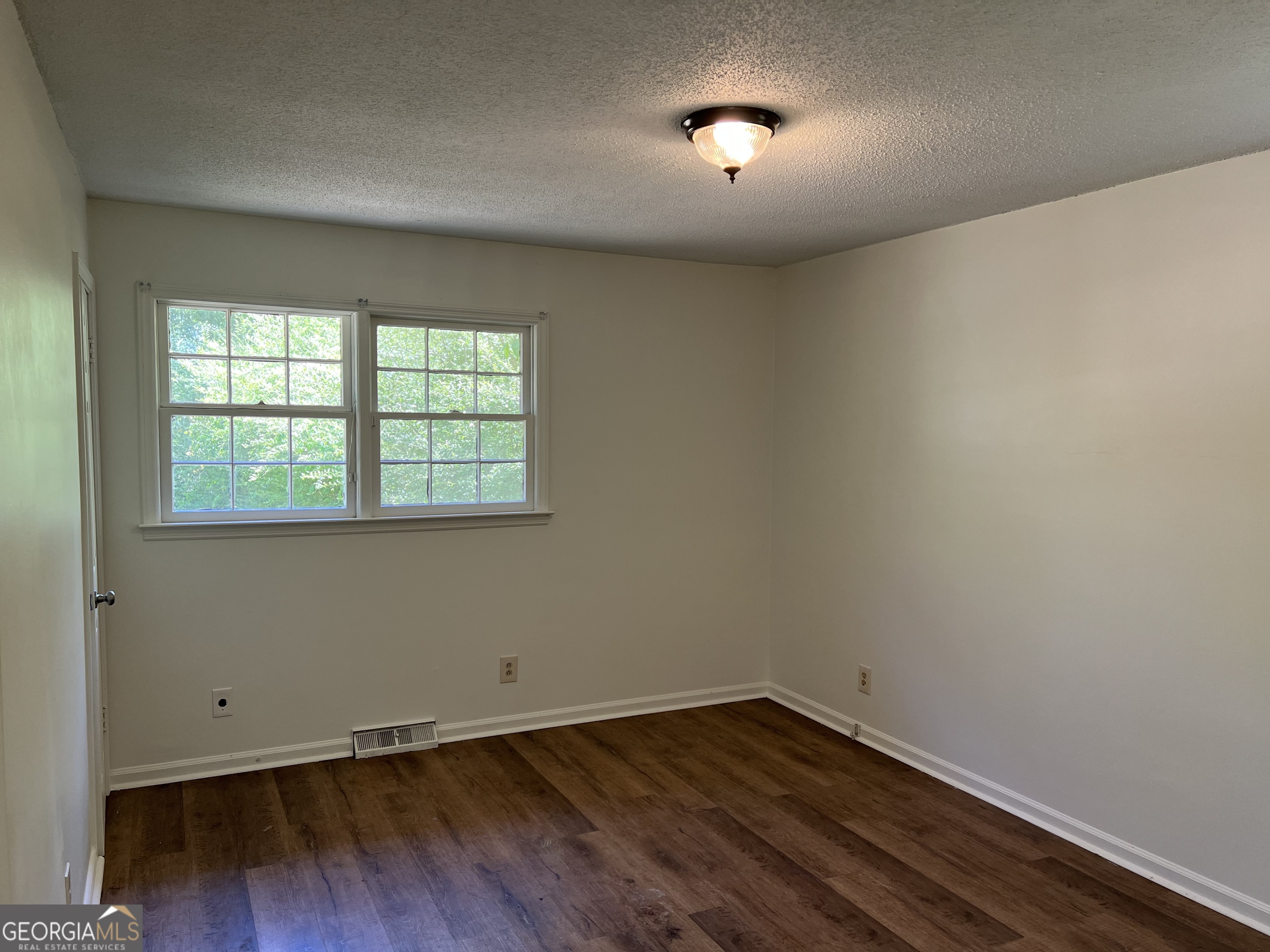 156 Deacon J Simmons Road Southwest Milledgeville, GA 31061 - Photo 17 of 22 an empty room with wooden floor and windows