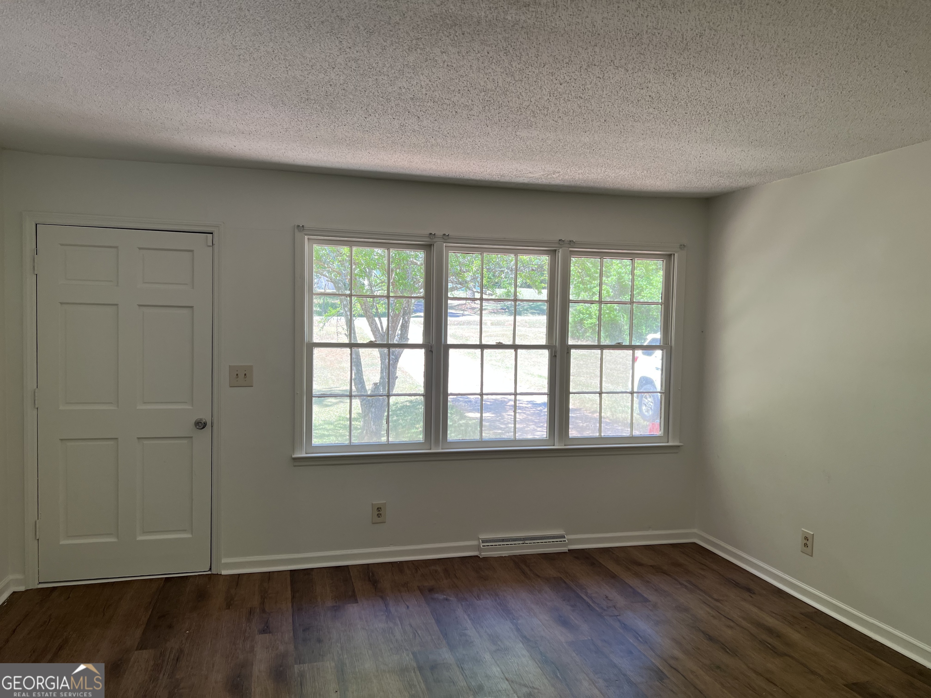 156 Deacon J Simmons Road Southwest Milledgeville, GA 31061 - Photo 5 of 22 an empty room with wooden floor and windows