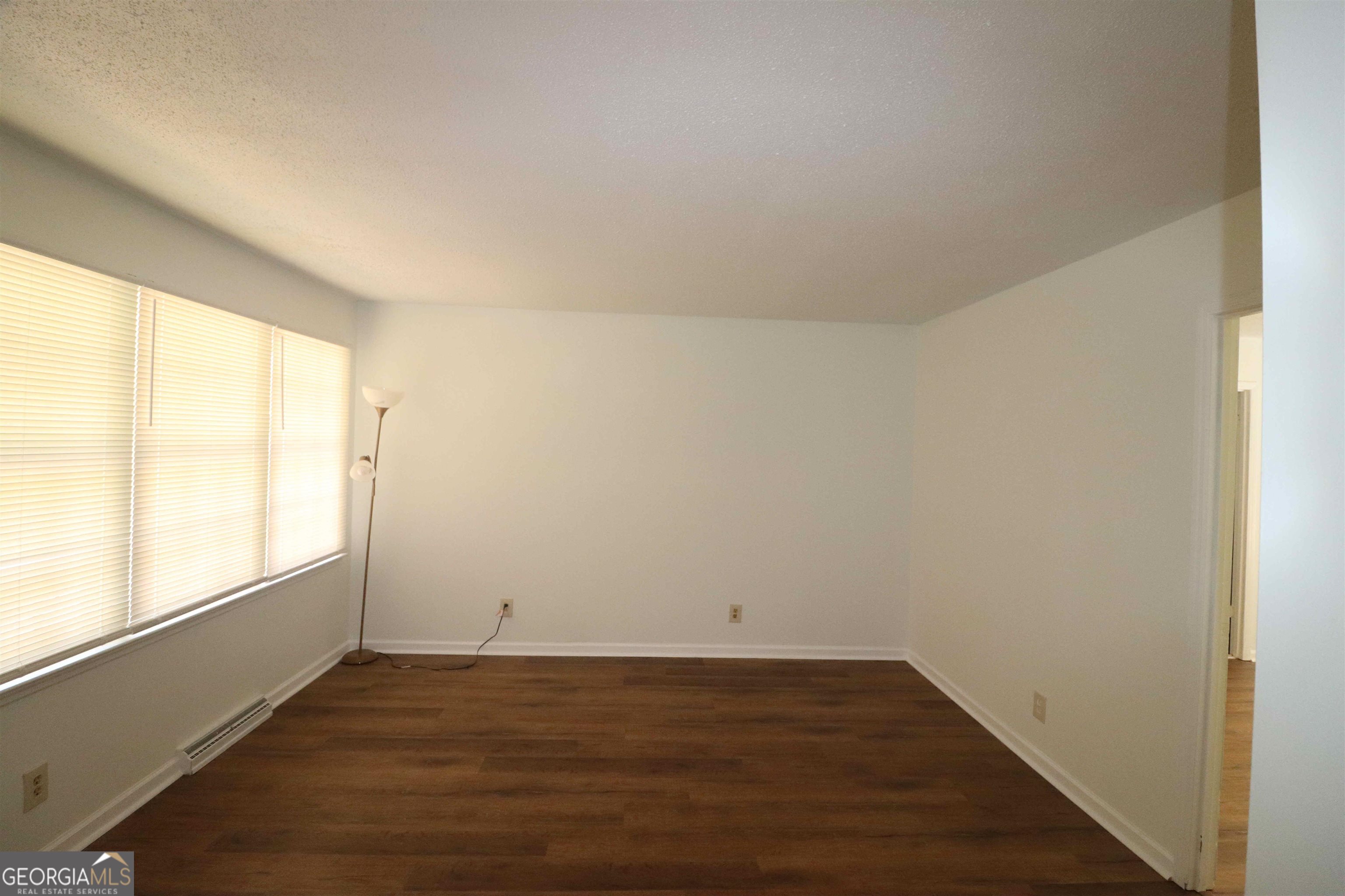 156 Deacon J Simmons Road Southwest Milledgeville, GA 31061 - Photo 6 of 22 an empty room with wooden floor and windows