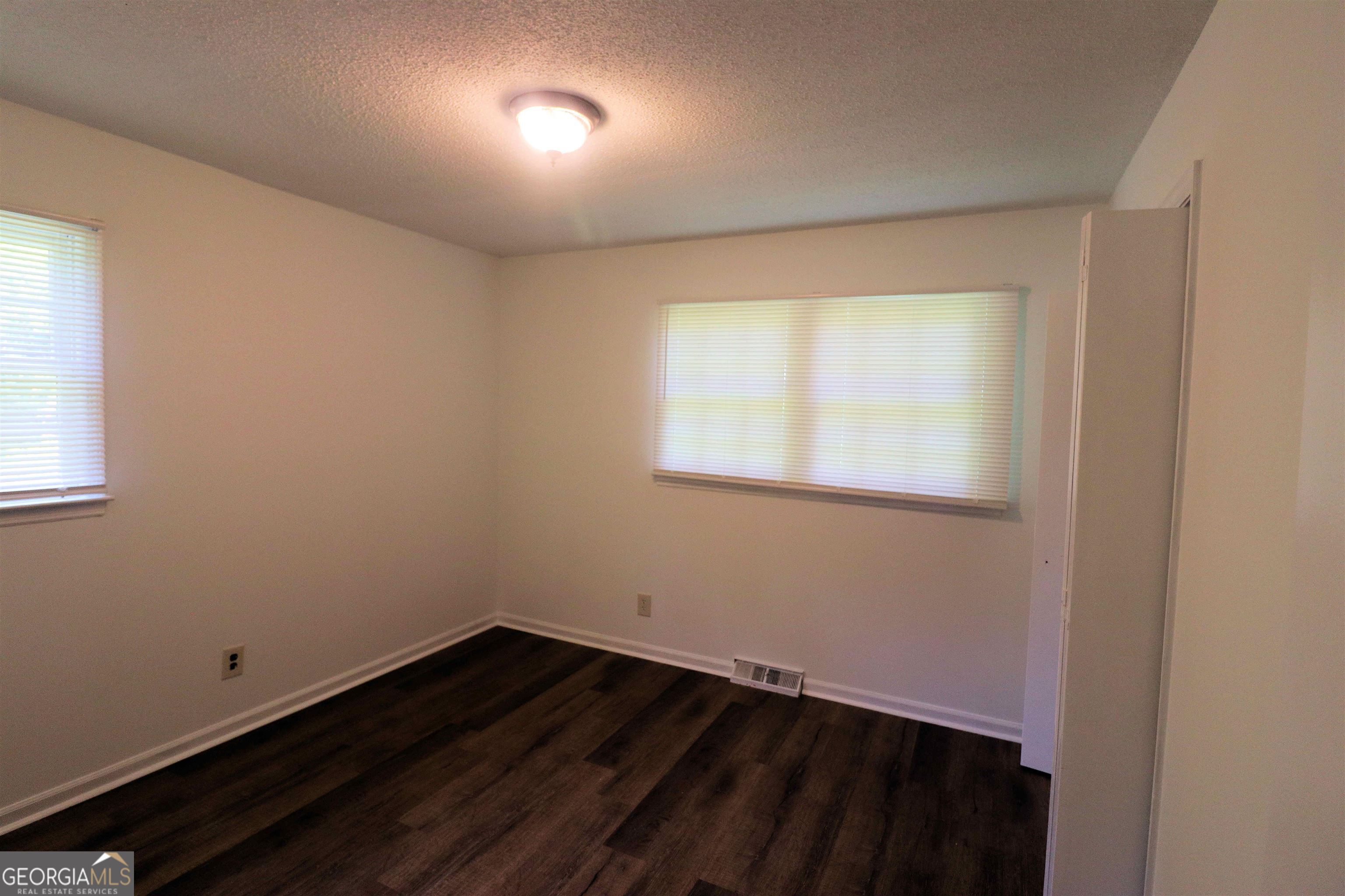 156 Deacon J Simmons Road Southwest Milledgeville, GA 31061 - Photo 9 of 12 an empty room with wooden floor and windows