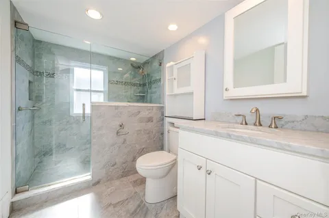 a bathroom with a granite countertop sink toilet a mirror and shower