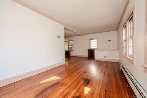 a view of empty room with wooden floor and window
