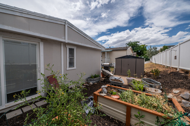 2600 North Hill Field Road, Unit 5 Layton, UT 84041 - Photo 24 of 33 Expansive backyard featuring a privacy fence, built-in planters, and an outdoor storage shed
