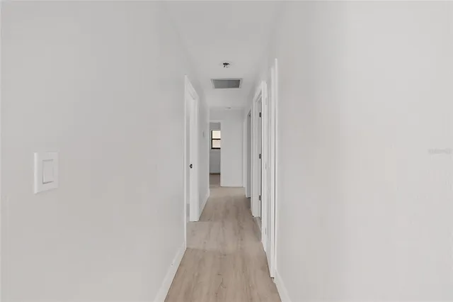 a view of a hallway with wooden floor and a bathroom