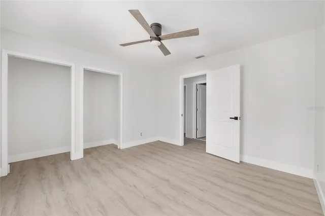 an empty room with wooden floor and ceiling fan