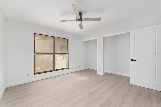 a view of an empty room with a window and wooden floor
