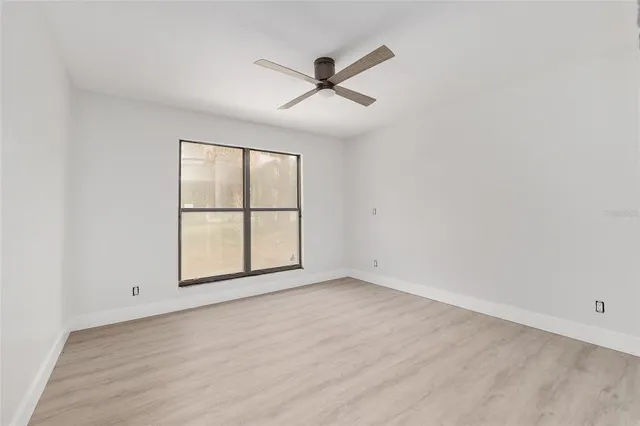 an empty room with window and ceiling fan