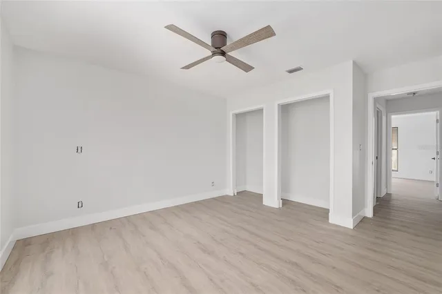 an empty room with wooden floor and ceiling fan