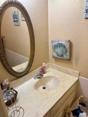a bathroom with a granite countertop bathtub shower sink vanity and toilet