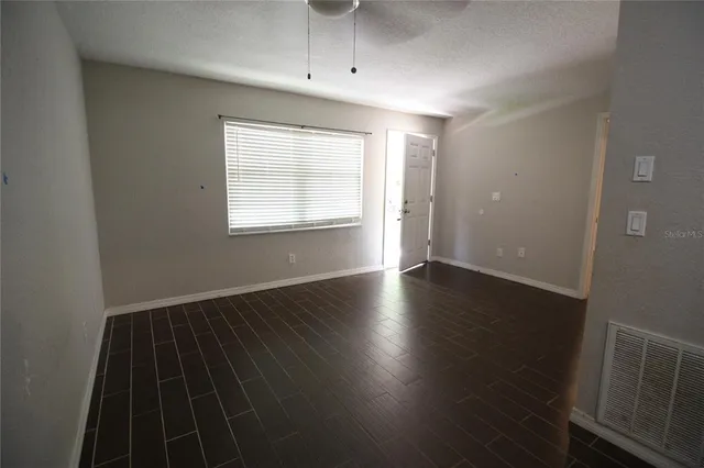 an empty room with wooden floor cabinet and windows