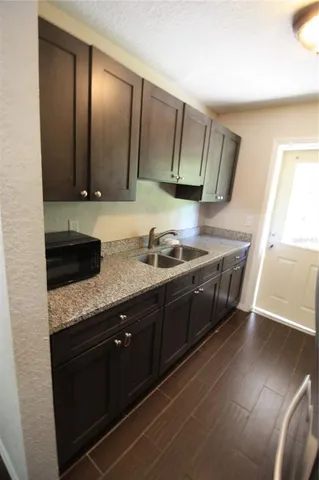 a kitchen with granite countertop a sink a stove and cabinets