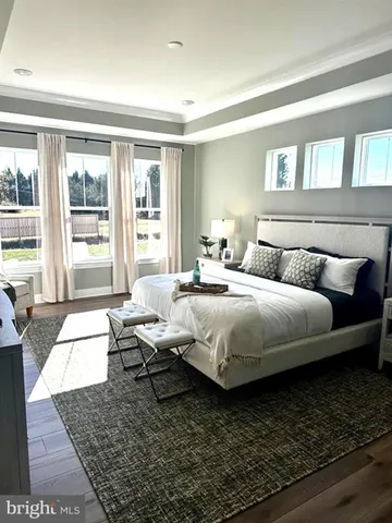 a bedroom with a bed wooden floor and a large window