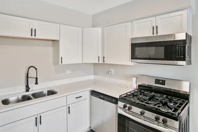 a kitchen with stainless steel appliances granite countertop white cabinets a stove top oven and granite counter tops
