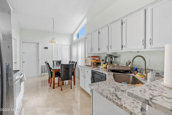 a kitchen with stainless steel appliances granite countertop a table chairs sink and cabinets