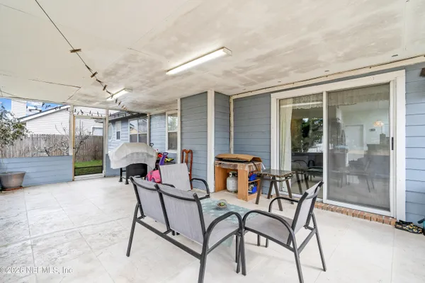 a patio with table and chairs and potted plants