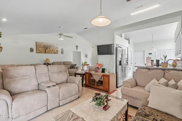 a living room with furniture kitchen view and a chandelier