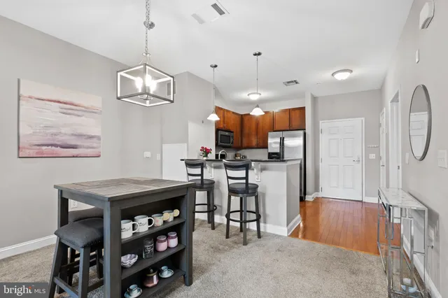 a kitchen with stainless steel appliances kitchen island granite countertop a table chairs and a refrigerator