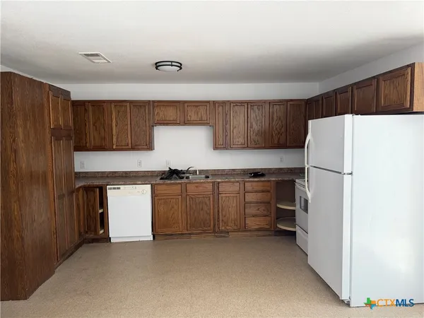 a kitchen with sink refrigerator and cabinets