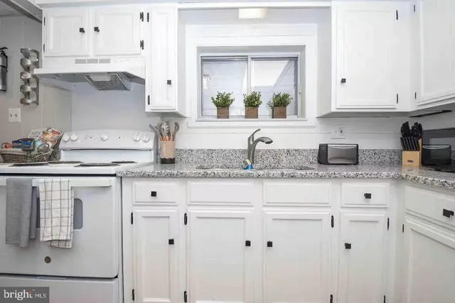 a kitchen with stainless steel appliances granite countertop white cabinets and a sink