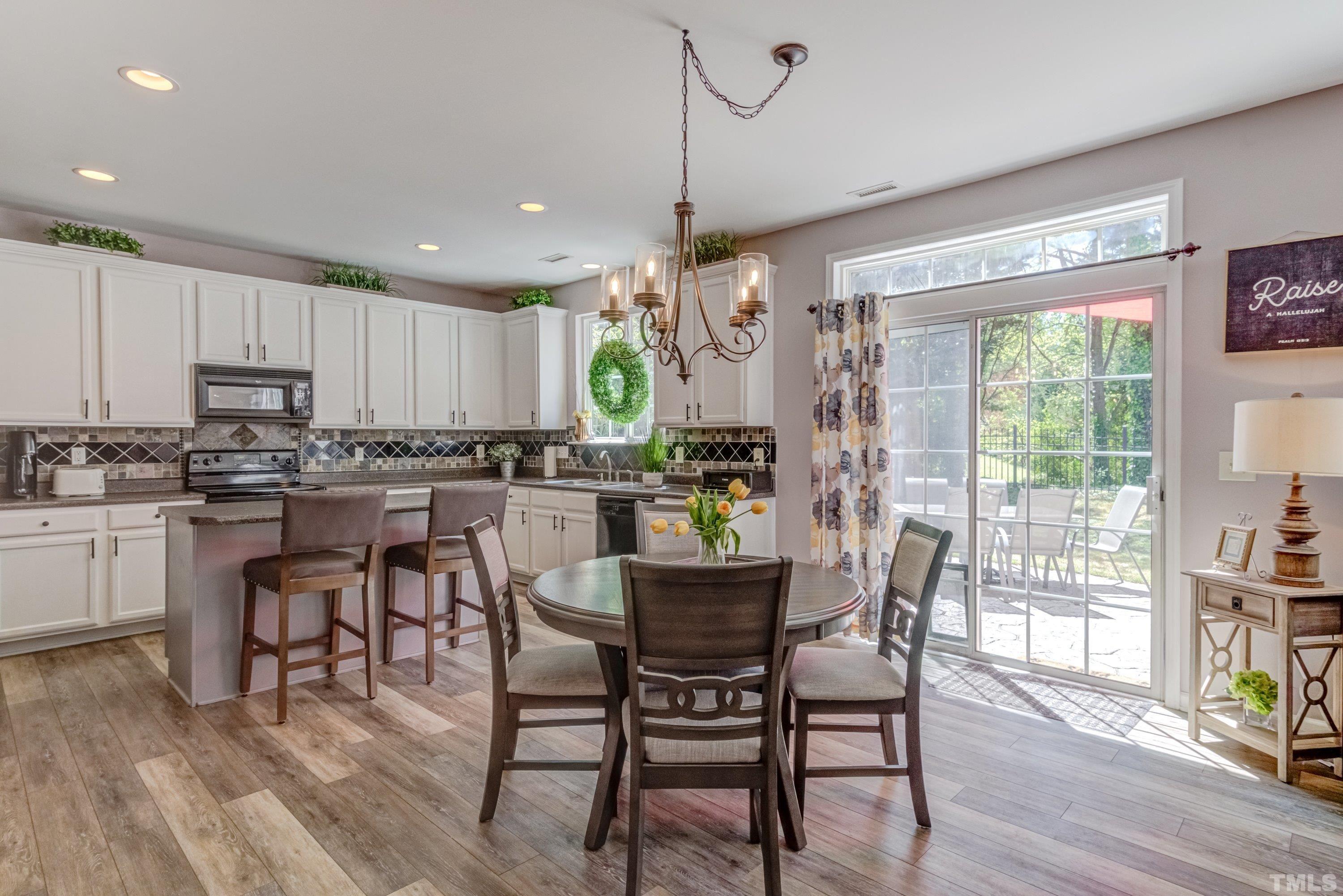 121 Ryder Cup Circle Raleigh, NC 27603 - Photo 11 of 43 a kitchen with kitchen island a dining table chairs and white cabinets