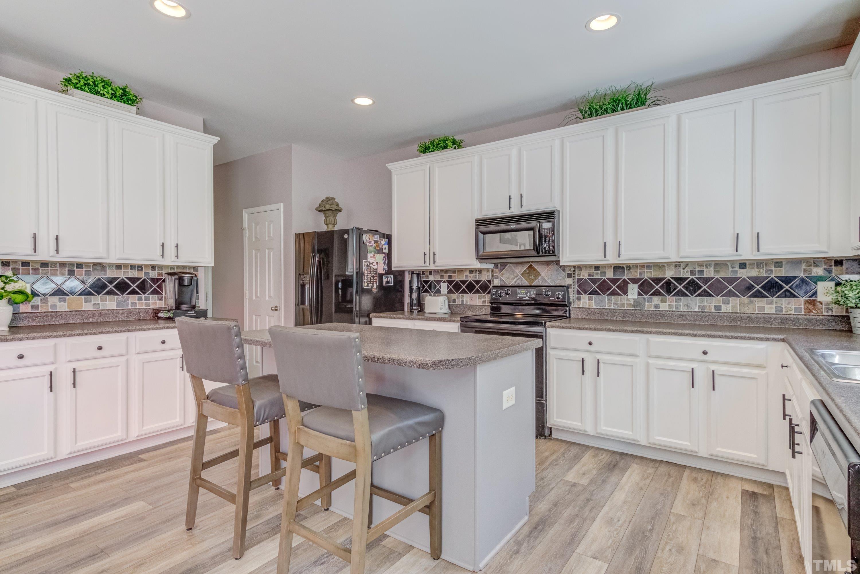 121 Ryder Cup Circle Raleigh, NC 27603 - Photo 15 of 43 a kitchen with stainless steel appliances granite countertop a stove a sink dishwasher and white cabinets with wooden floor