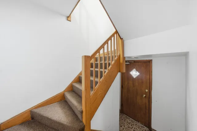 a view of staircase with railing and white walls