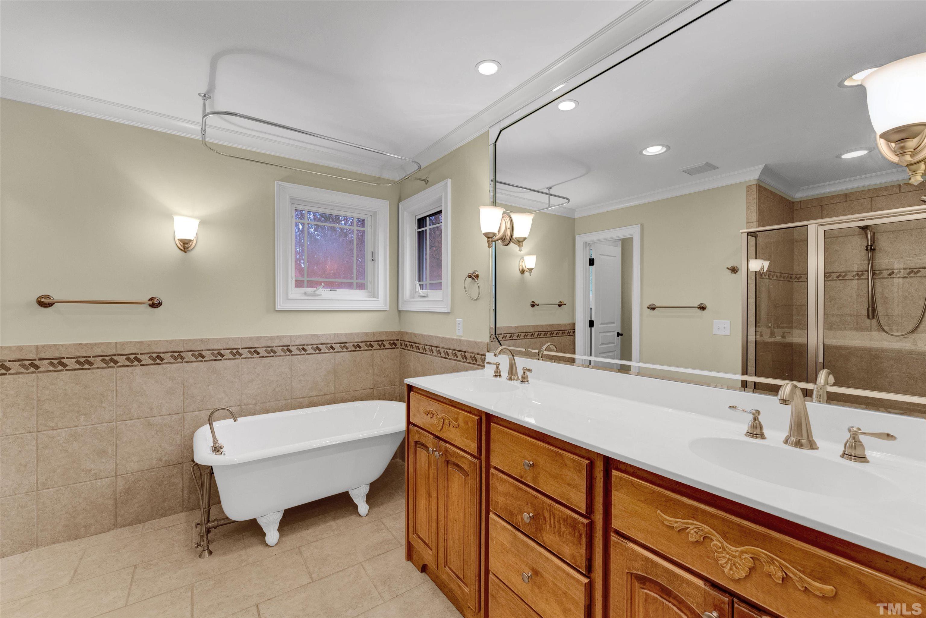 1201 Town Side Drive Apex, NC 27502 - Photo 23 of 40 a bathroom with a double vanity sink a mirror and a bathtub
