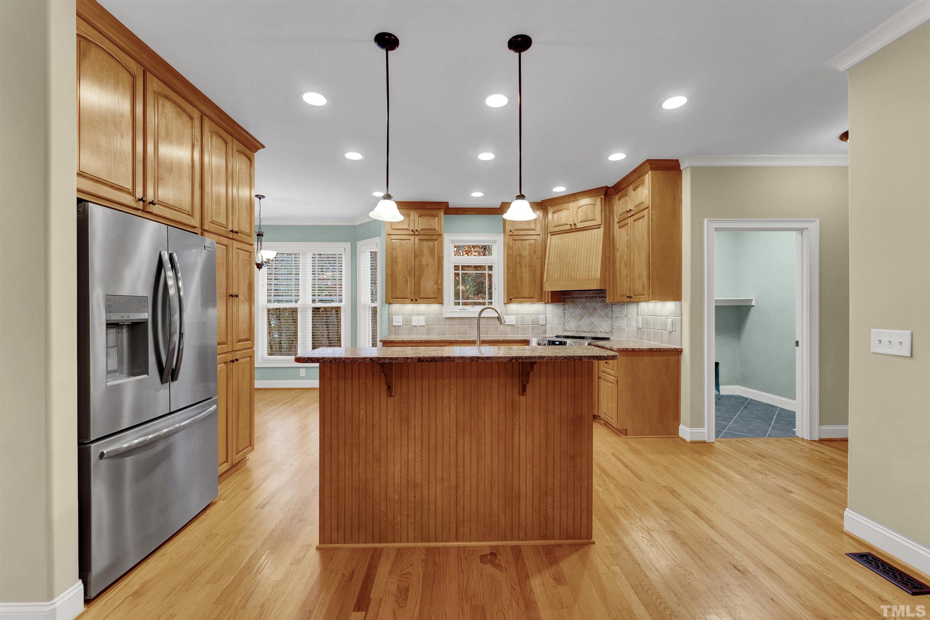 1201 Town Side Drive Apex, NC 27502 - Photo 10 of 40 a large kitchen with stainless steel appliances kitchen island granite countertop a refrigerator a oven and a wooden floors