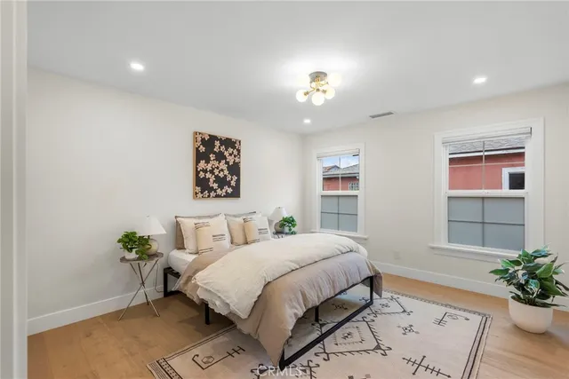 a bedroom with a bed potted plant with the wooden floor