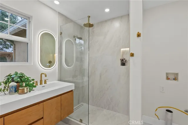 a bathroom with a granite countertop shower a sink and a mirror