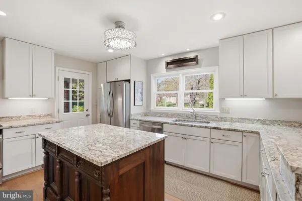 a kitchen with granite countertop stainless steel appliances a sink stove and cabinets