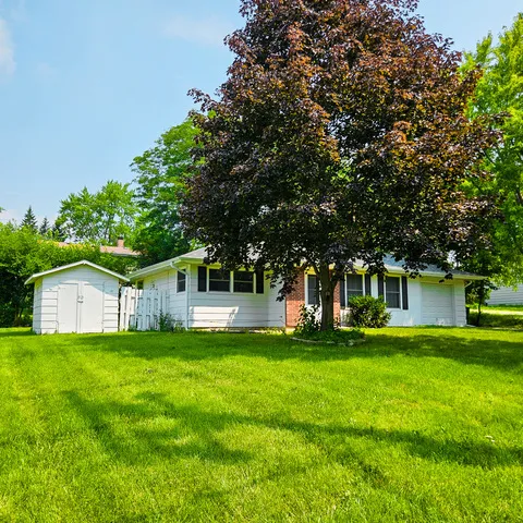 a view of a house with a big yard and large trees