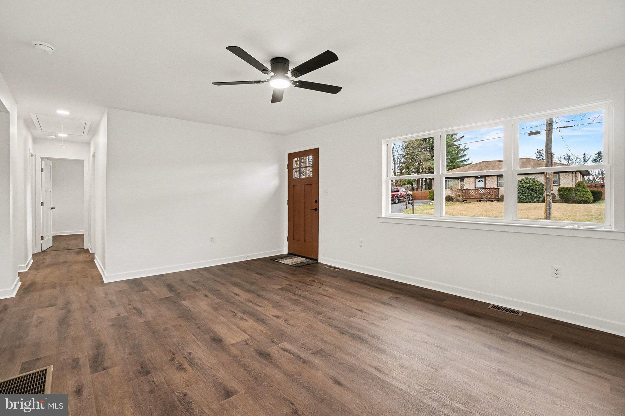 6216 Locust Street Harrisburg, PA 17112 - Photo 4 of 28 a view of a big room with wooden floor a ceiling fan and windows