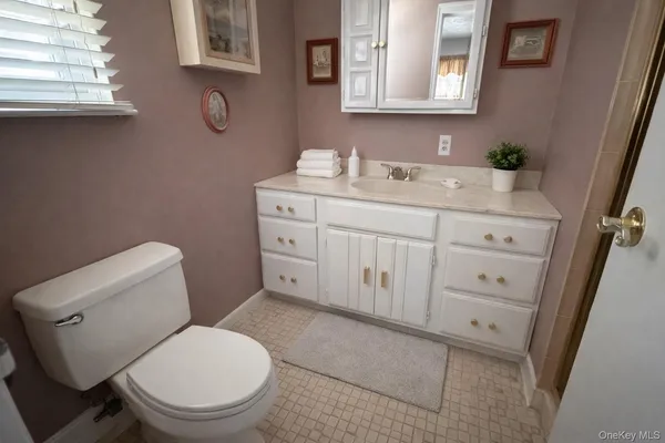 a bathroom with a granite countertop toilet sink and mirror