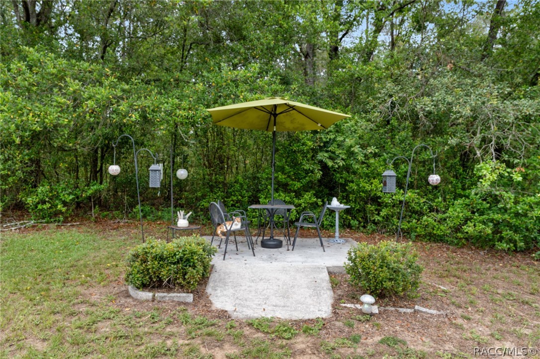 3355 South Highlands Avenue Inverness, FL 34452 - Photo 29 of 30 a view of a garden with a table and chairs under an umbrella