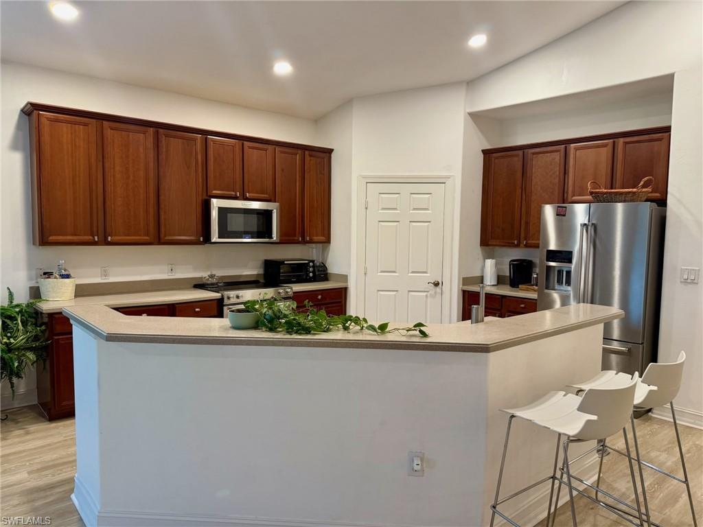 1252 Rialto Way, Unit 202 Naples, FL 34114 - Photo 14 of 26 a kitchen with stainless steel appliances granite countertop a refrigerator stove a sink and a microwave