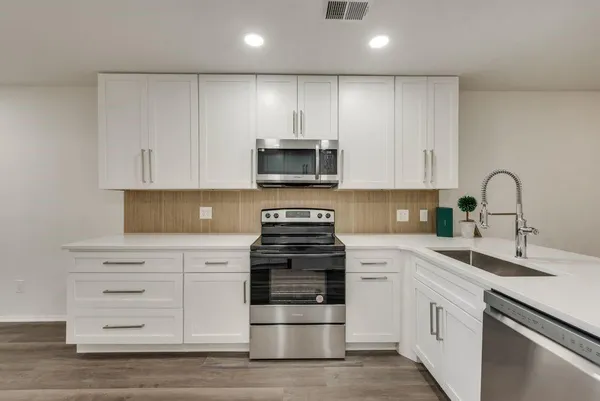 a kitchen with granite countertop white cabinets and stainless steel appliances