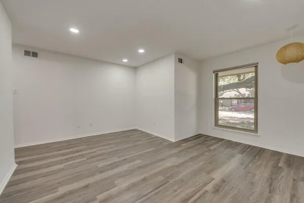 a view of an empty room with wooden floor and a window