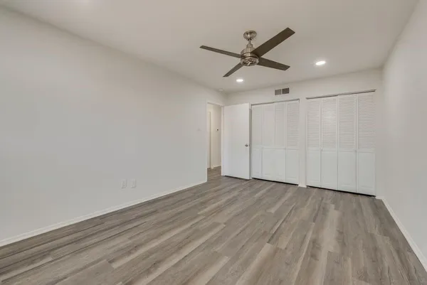 a view of a big room with wooden floor a ceiling fan and staircase