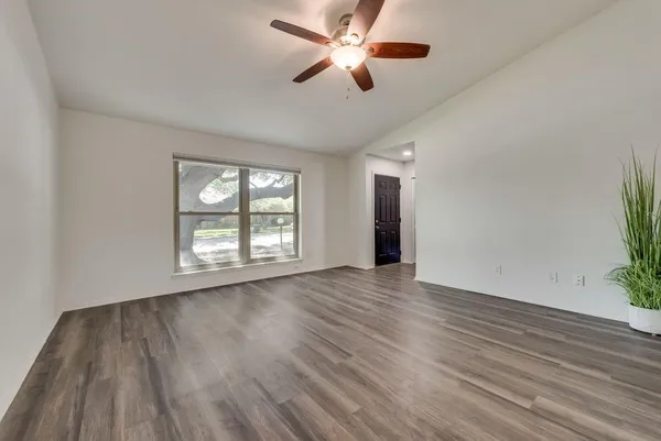 a view of an empty room with wooden floor and a window