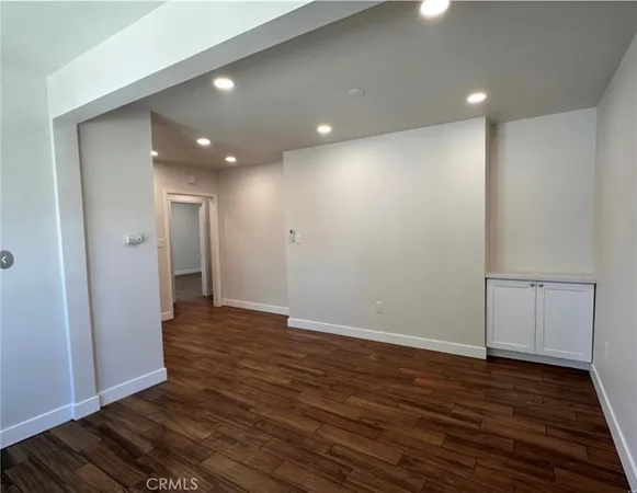 a view of an empty room with wooden floor and closet