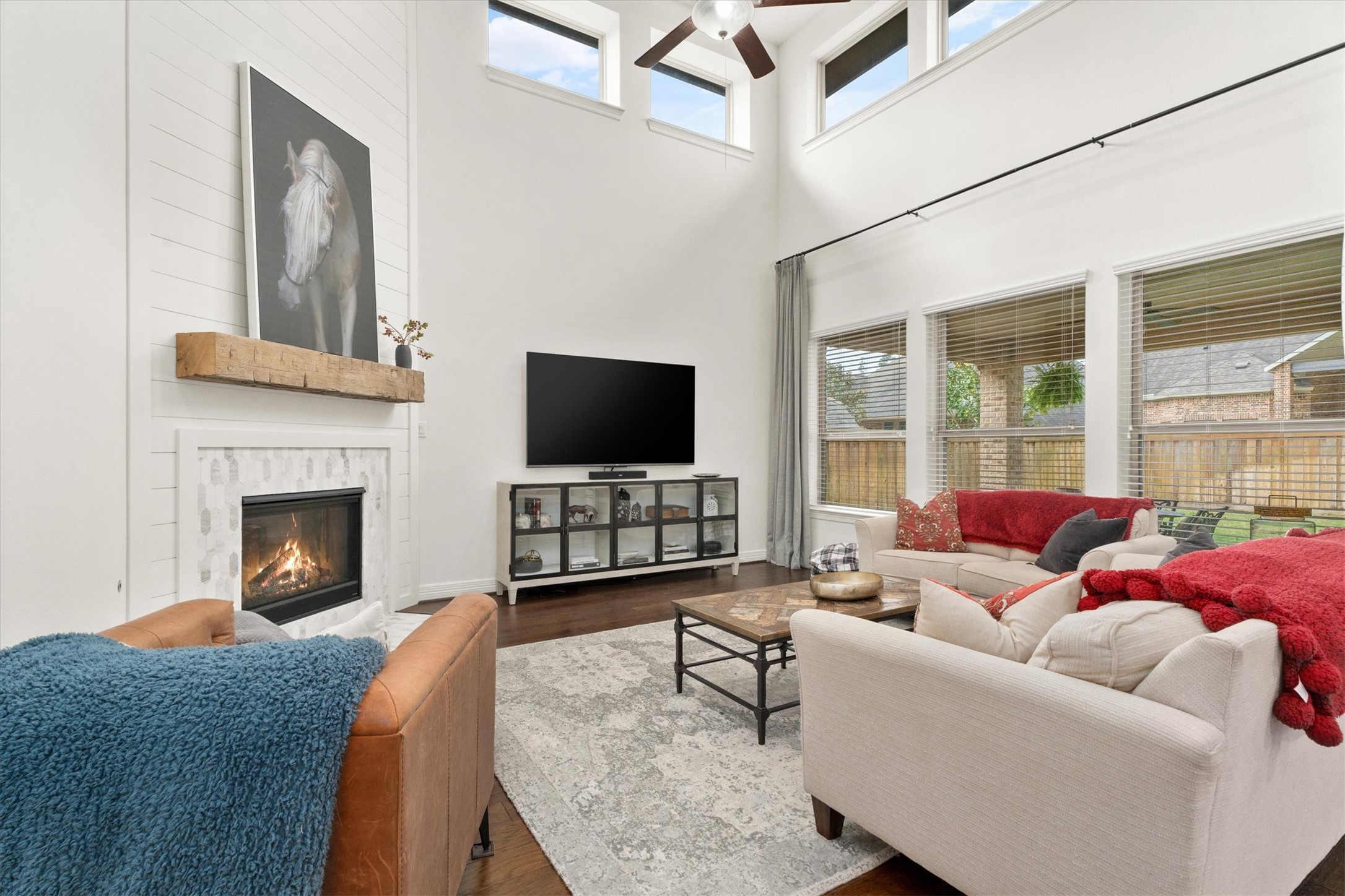 27121 Holtwood Grove Road Magnolia, TX 77354 - Photo 13 of 50 Step into this spacious and light-filled family room, where soaring ceilings and an abundance of windows create an airy, open feel. The centerpiece is the beautifully updated fireplace, showcasing modern shiplap detailing, an elegant tile surround, and a charming natural wood mantel – the perfect blend of style and warmth. Whether hosting guests or enjoying a quiet evening, this room offers the ideal setting.